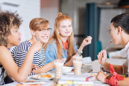 Pleasant discussion. Positive delighted boy keeping smile on his face while eating dessertの写真素材