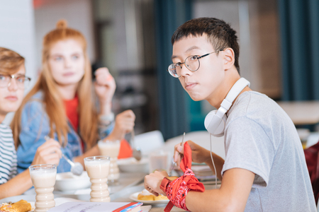 Deep in thoughts. Attentive brunette male person pressing lips while looking aside, sitting in semi positionの写真素材