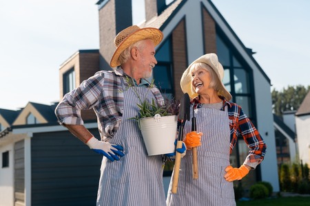 Big house. Smiling joyful couple looking at each other while standing next to the house