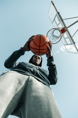 Basketball game. Low angle of an orange basketball ball being in hands of a nice Afro American manの写真素材