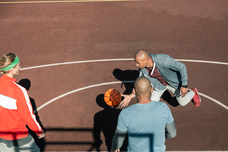 Basketball game. Top view of pleasant young men catching the ball while playing basketballの写真素材