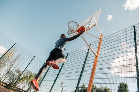 During the training. Nice strong young man jumping up while playing basketball aloneの写真素材