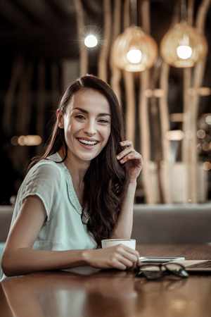 Pretty brunette. Amazing female person keeping smile on her face while posing on cameraの写真素材