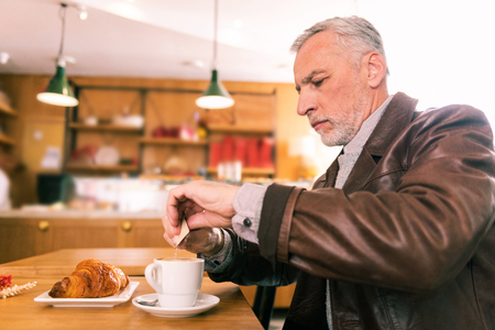 Businessman in bakery. Grey-haired businessman spending morning in French bakery trying croissantの写真素材