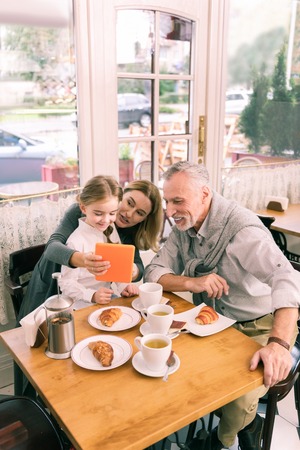 Beaming grandparents. Happy beaming grandparents eating morning croissants with cute little granddaughterの写真素材