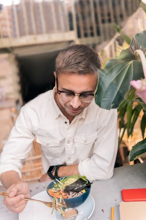 Avocado salad. Top view of handsome dark-haired man wearing glass eating delicious avocado saladの写真素材