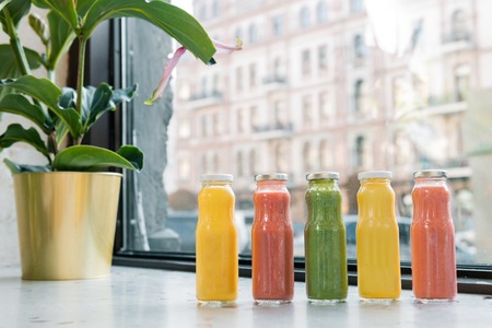 Five juices. Five freshly squeezed fruit juices standing near decorative plant on the window sillの写真素材