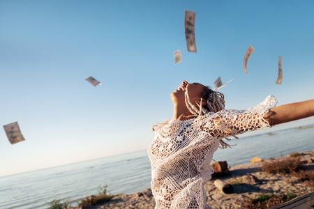 Money in air. Successful prosperous freelancer with white dreadlocks throwing her money in the airの写真素材