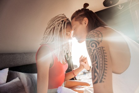 Meet sunshine. Cute loving couple meeting sunshine in their compact trailer standing in natureの写真素材