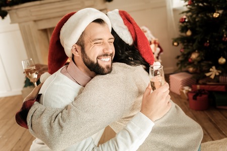 Warm emotions. Joyful nice positive couple smiling and hugging each other while celebrating New Years Eveの写真素材
