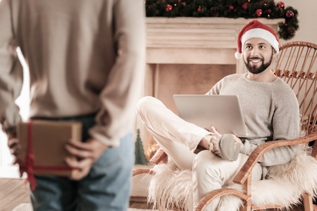 Come to me. Attractive freelancer being high-spirited, holding laptop while keeping smile on his faceの写真素材