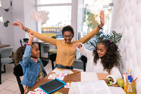 Successful class. Nursery teacher and two cute little preschool girls feeling happy after successful classの写真素材