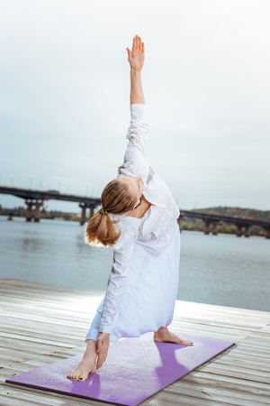 The triangle pose. Young woman performing yoga asanas near the riverの写真素材
