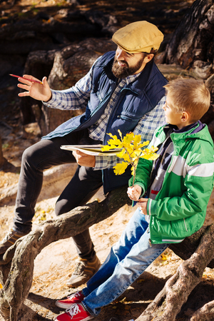 Pleasant conversation. Delighted nice man talking to his son while being in the parkの写真素材