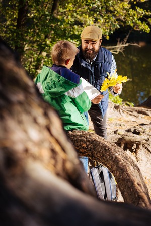 Positive mood. Joyful delighted man talking to his son while having a walk in the forestの写真素材