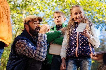 Biology lesson. Nice cheerful girl standing with her teacher while having an outdoor biology lessonの写真素材