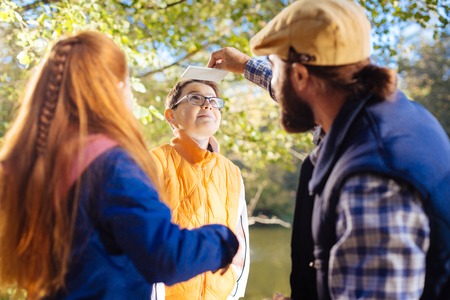 What is this. Positive nice boy holding his head up while looking at the interesting object on his headの写真素材