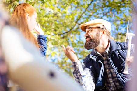Environmental activity. Pleasant smart teacher pointing at his pupil while holding a windmill modelの写真素材