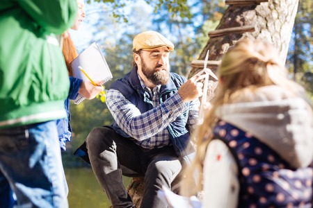 Ecological issues. Smart adult man speaking about windmills while sitting in front of pupilsの写真素材