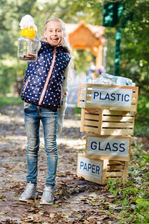 Eco friendliness. Cute cheerful girl showing you the batteries while being happy to help the environmentの写真素材