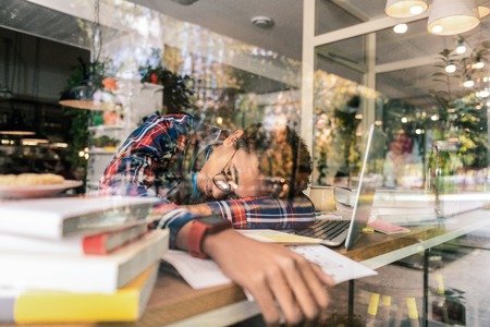 No energy. Cheerless sad student lying on the table while feeling very tiredの写真素材