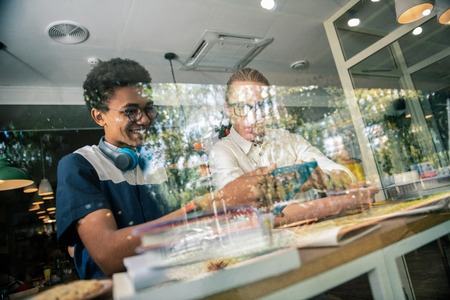 Additional classes. Joyful positive student sitting together with his teacher while having an additional class with himの写真素材