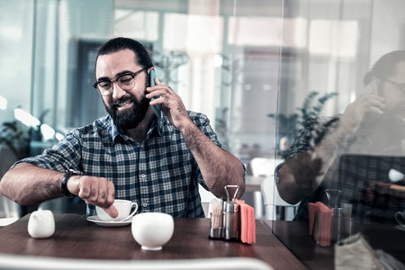 Arrange meeting. Busy businessman wearing squared shirt calling his colleague while arranging meetingの写真素材