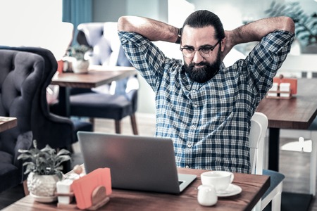 Tired freelancer. Bearded dark-haired freelancer wearing glasses feeling tired after working for longの写真素材