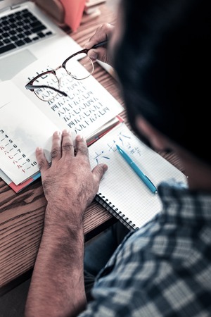 Study hieroglyphs. Top view of dark-haired mature businessman studying hieroglyphs on his weekendの写真素材