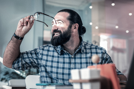 Squared shirt. Bearded dark-haired man wearing squared shirt looking into the window sitting in cafeteriaの写真素材