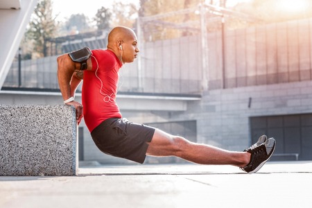 Young and strong. Handsome well built man doing physical exercises while developing his strengthの写真素材