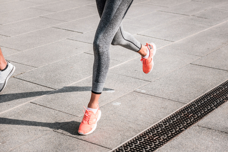 Female runner. Close up of skinny beautiful female legs during the running marathon