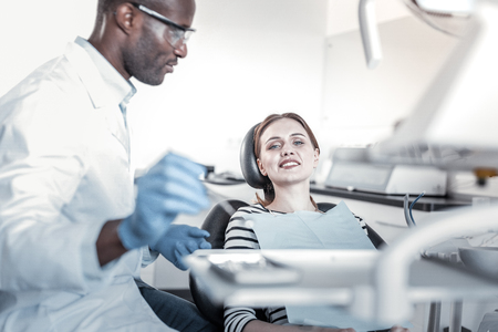 Relaxed atmosphere. Attentive stomatologist sitting in semi position while examining his visitorの写真素材