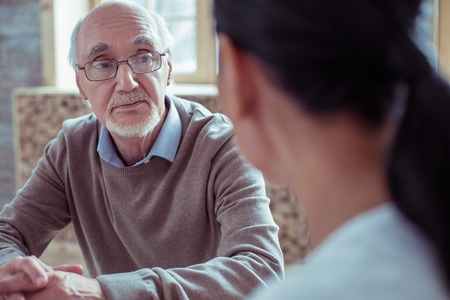 So sad. Attentive mature male wrinkling forehead while looking at his international friendの写真素材