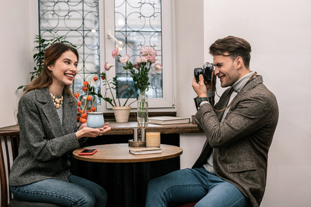 Photoshoot Man taking picture of smiling woman holding a cup of cocoaの写真素材