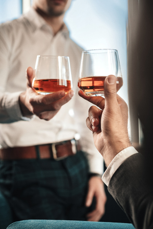 Stylish man. Stylish man wearing squared trousers drinking whisky with his business partner