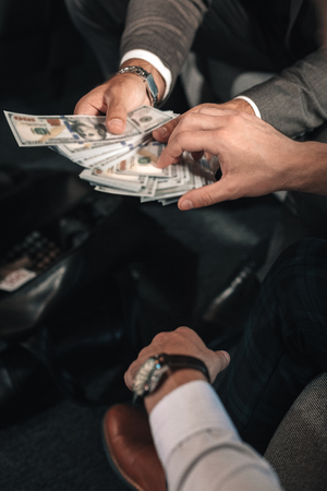 Receiving payoff. Man wearing hand watch and white shirt receiving payoff from business partnerの写真素材