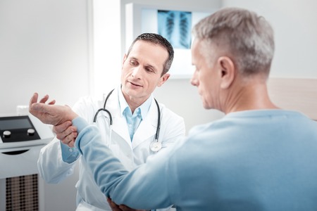 Lets count. Competent doctor turning head while sitting opposite his patientの写真素材