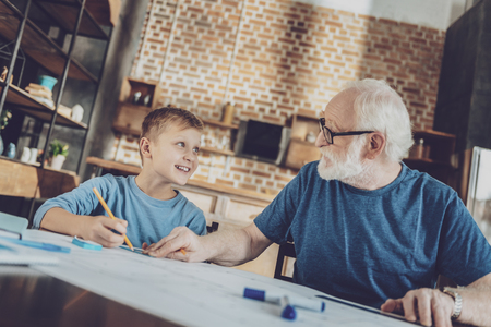 Pleasure communication. Attentive mature man turning head while talking to his grandfatherの写真素材