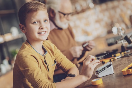 Helping my granddad. Handsome kid keeping smile on face while looking at cameraの写真素材