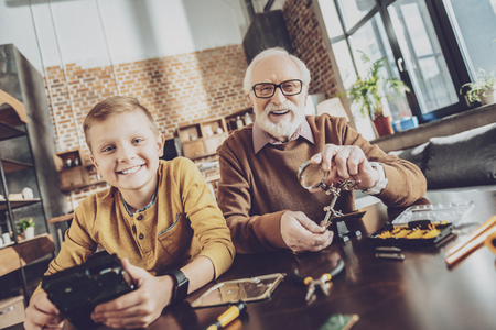 Join us. Joyful males repairing gadgets while looking straight at cameraの写真素材