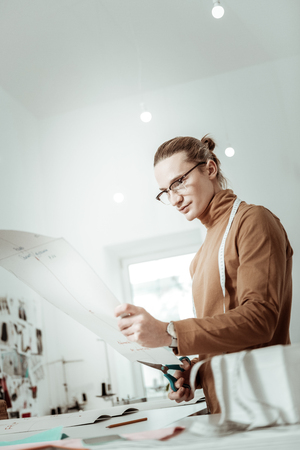 Work results. Attractive young designer from a fashion studio wearing a brown garment looking at the sketchの写真素材