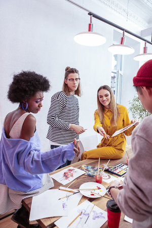 Students drawing. Company of creative talented art school students standing near table and drawingの写真素材