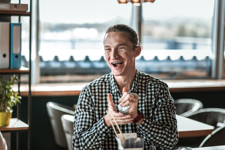 Be happy. Cheerful young man making ball from paper while communicating with his colleaguesの写真素材
