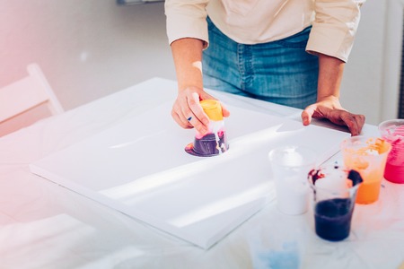 Marble painting. Creative promising artist wearing jeans performing marble painting on white paper
