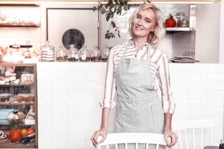 Professional baker. Positive happy woman wearing an apron while working in the bakeryの写真素材