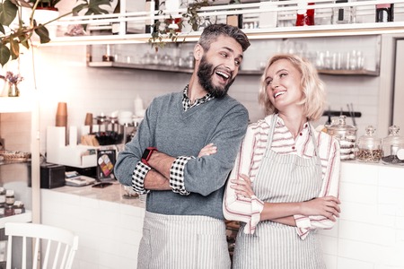 Pleasant couple. Joyful nice man looking at his girlfriend while standing in their cafeの写真素材