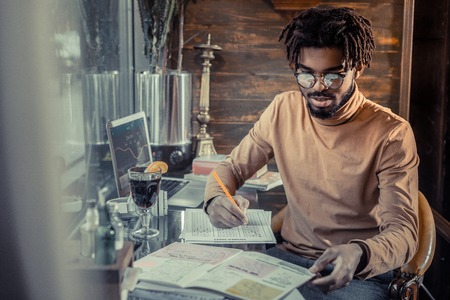 Do analytics. Pleased bearded man bowing head while checking documentsの写真素材