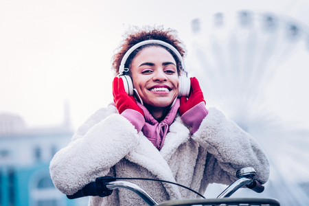 Enjoy your life. Charming brunette raising arms while touching her headphonesの写真素材