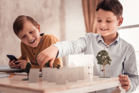 Model of house. Two curious schoolboys feeling extremely joyful while building model of detached houseの写真素材